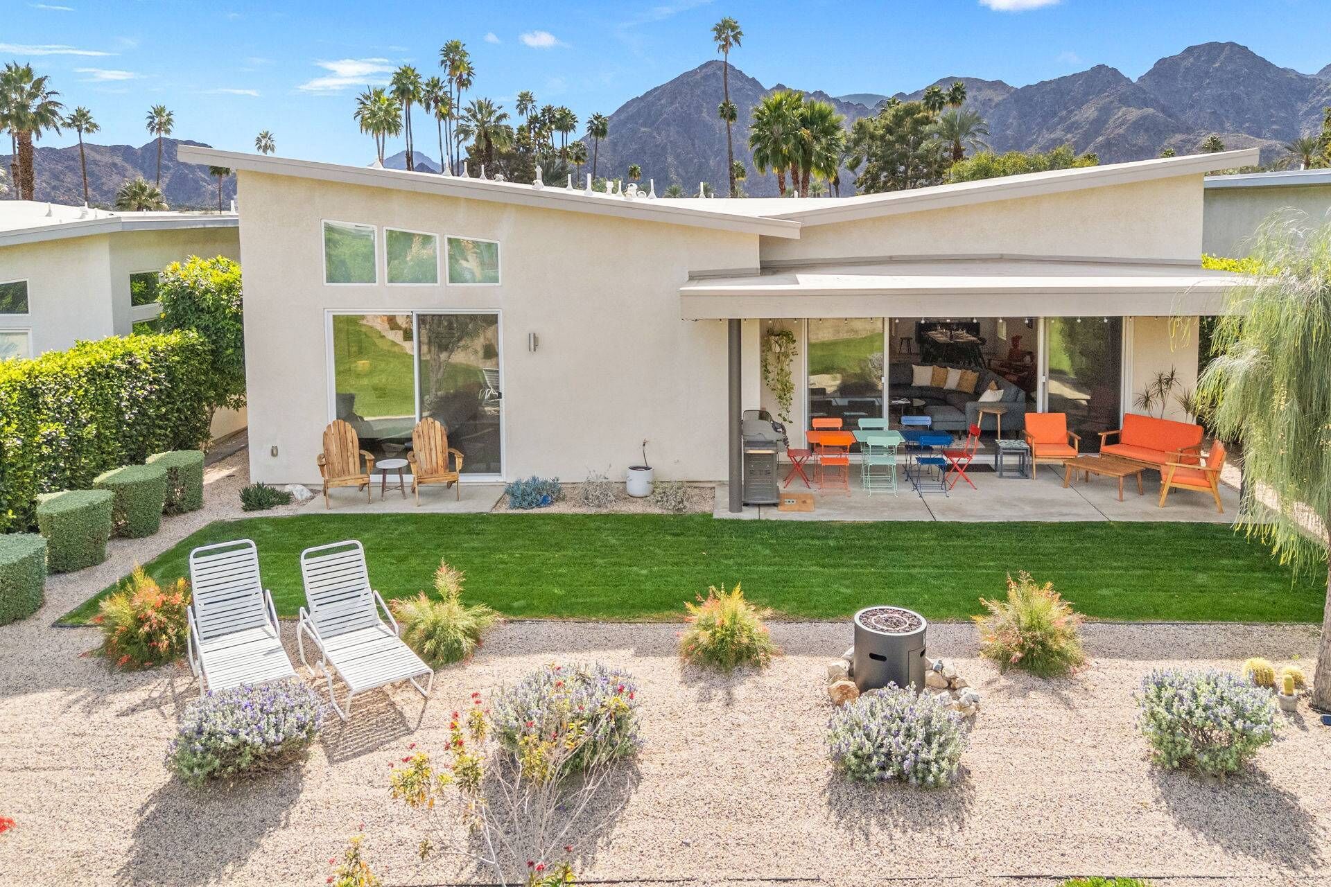 Una casa moderna con un patio, mobiliario exterior y vistas a las montañas.