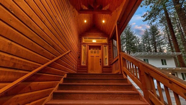 A wooden staircase leading to a door, surrounded by wooden walls and railings, with a view of trees and a building in the background. - Tahoe Trailside Lodge: Hot Tub, AC, Walk-to-Trail (South Lake Tahoe)