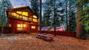 A wooden cabin with a balcony, surrounded by tall trees and a picnic table. - Tahoe Trailside Lodge: Hot Tub, AC, Walk-to-Trail (South Lake Tahoe)