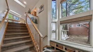 A staircase with wooden railings, a bench with baskets, and a view of a wooden garage through large windows. - Tahoe Trailside Lodge: Hot Tub, AC, Walk-to-Trail (South Lake Tahoe)
