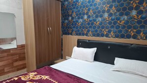 Quarto com cama, guarda-roupa de madeira e parede com padrão de azulejos azuis e laranja.