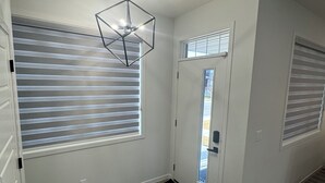 A room with a sloped ceiling, a geometric light fixture, a sliding door, and a black doormat. - Family-Friendly Calgary Retreat | Gateway to Banff (Calgary)