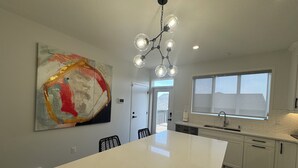 A modern kitchen with a central island, a large abstract painting, and a view through the window. - Family-Friendly Calgary Retreat | Gateway to Banff (Calgary)