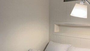 Ein Hotelzimmer mit Bett, Nachttisch und Wandregal.