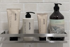 Un estante de baño con diversos artículos de aseo personal, incluyendo un set de cuidado para el cabello, una loción corporal y un gel de ducha.