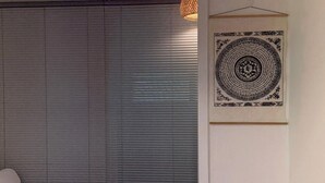 Ein Zimmer mit geschlossener Schiebetür, einer Hängeleuchte und einem gerahmten Kunstwerk an der Wand.