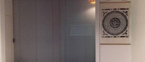 A room with a closed sliding door, a hanging light fixture, and a framed artwork on the wall.