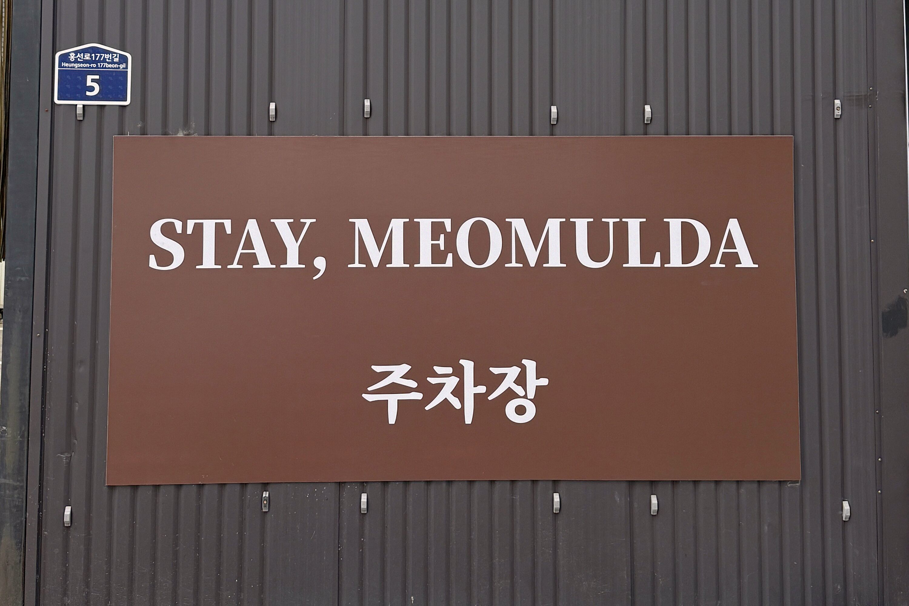 A sign with the text "STAY, MEOMULDA" and "주차장" indicating a parking area.