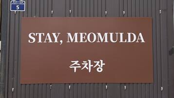 Ein Schild mit dem Text „STAY, MEOMULDA“ und „주차장“, das einen Parkplatz kennzeichnet.