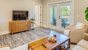 A living room with a wooden entertainment center, a television, a coffee table with decorative items, and a sofa. - Family Getaway in Calabash w/ Pool; 9 Mi to Beach (Calabash)