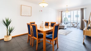 A modern hotel room with a dining area, a sofa, a balcony with a view, and a potted plant. - GuestReady - Charming Apartment with Ocean Views (Caniço)
