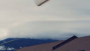 Een berg met bewolkte lucht en een dak met dakpannen.