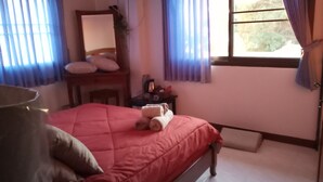 Een slaapkamer met een bed, een stoel, een tafel en een raam.