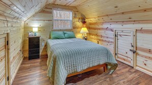 Ein gemütliches Schlafzimmer mit Holzboden, einem Bett mit grüner Tagesdecke, einem Nachttisch mit Lampe und einer Kommode.