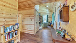 Ein Interieur einer Holzhütte mit Bücherregal, Esstisch und Kamin.