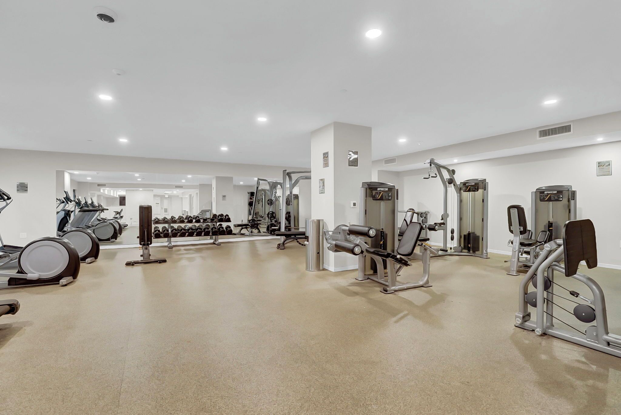 A gym with treadmills, dumbbells, and weight machines.