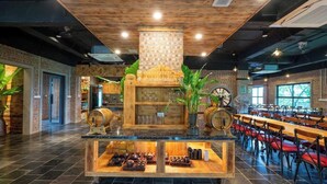 Un ristorante con un'area bar centrale, tavoli e sedie in legno e una selezione di piatti esposti al bancone.