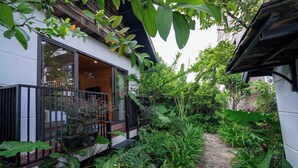 Un rigoglioso giardino con un vialetto in pietra che conduce a un edificio con ampie finestre e un balcone.