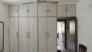 Ein Zimmer mit großem Kleiderschrank, Deckenventilator und einem Sessel.