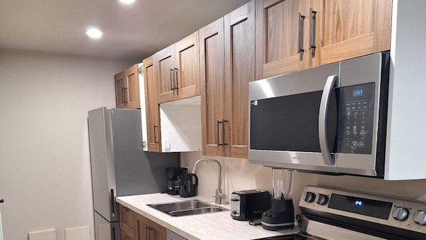 A modern kitchen with wooden cabinets, stainless steel appliances, a microwave, a coffee maker, and a dishwasher.
