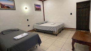 A room with two beds, a wooden table, and a ceiling light fixture.