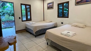 A room with two beds, a small table, and a ceiling light fixture.