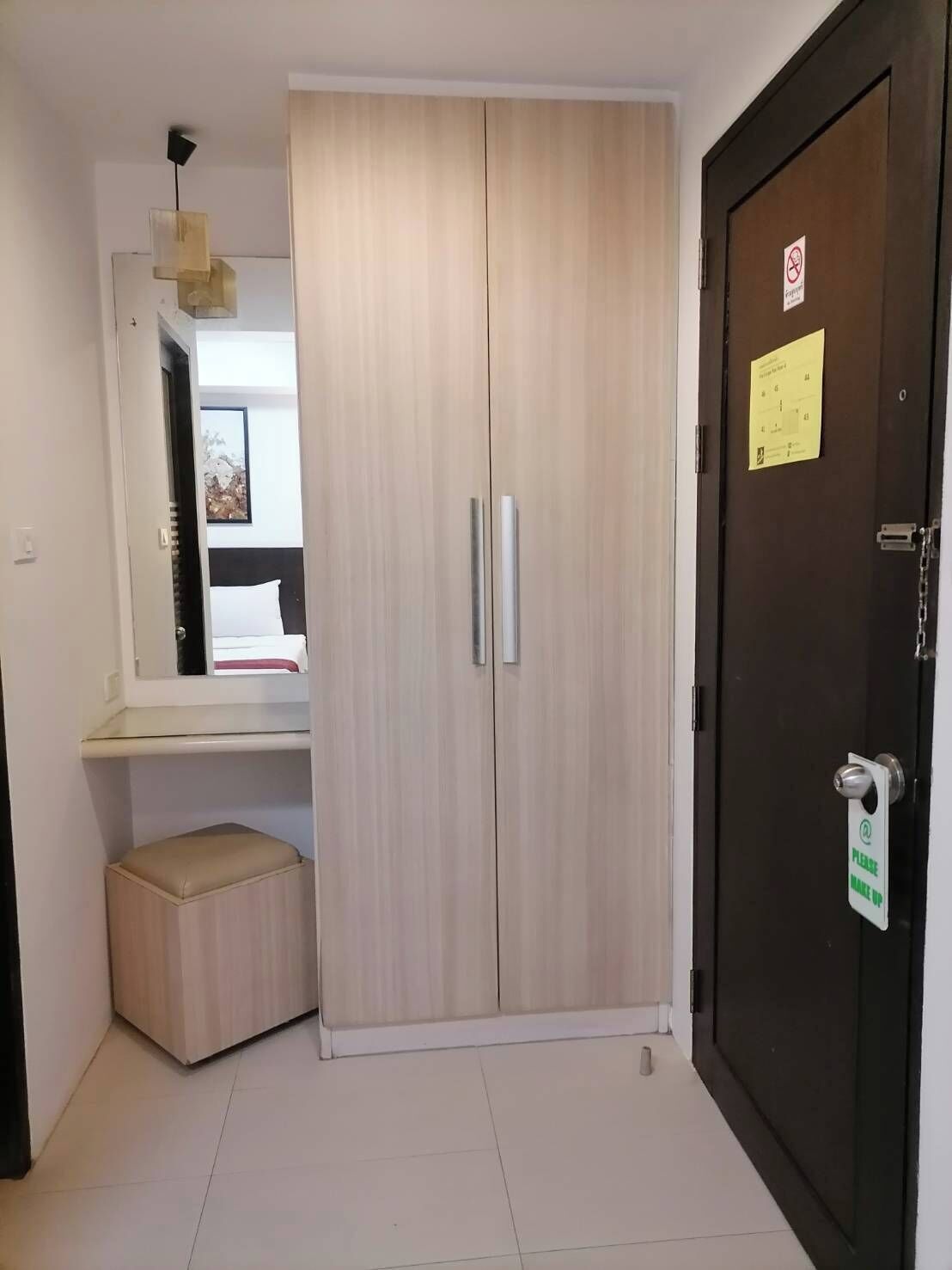 A room with a wardrobe, a bench, and a door with a sign.