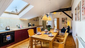 A modern kitchen with a skylight, wooden dining table, and wicker chairs. - Apartment 'Stadt-Loft' with Private Terrace, Wi-Fi, and Air Conditioning (Nordhausen)