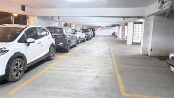 A parking garage with multiple rows of parked cars, concrete floors, and a 'No Parking' sign.