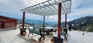Terraza exterior con pérgola, asientos y vistas a montañas.