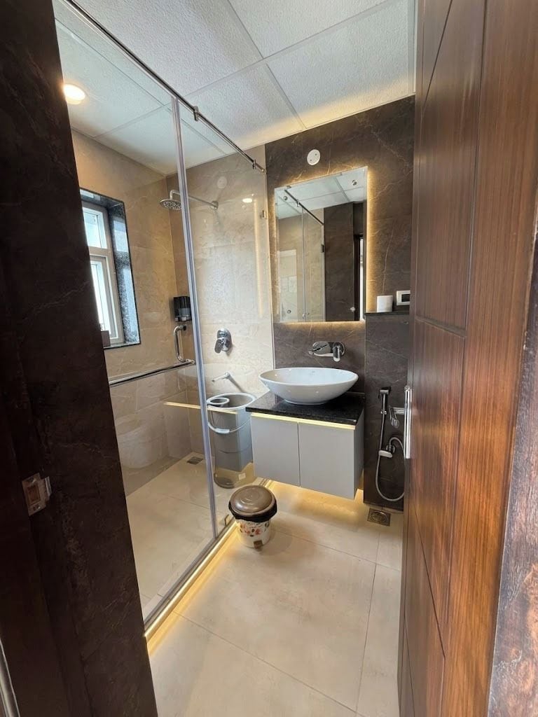 Un baño moderno con cabina de ducha de vidrio, un lavamanos blanco y un inodoro.