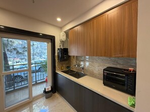 A modern kitchen with a built-in oven, a sink, and wooden cabinets. - CDS Luxury Homestay Shimla (Shimla)