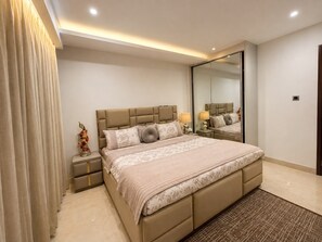 Un dormitorio moderno con una cama grande, mesitas de noche, un espejo y una cortina.