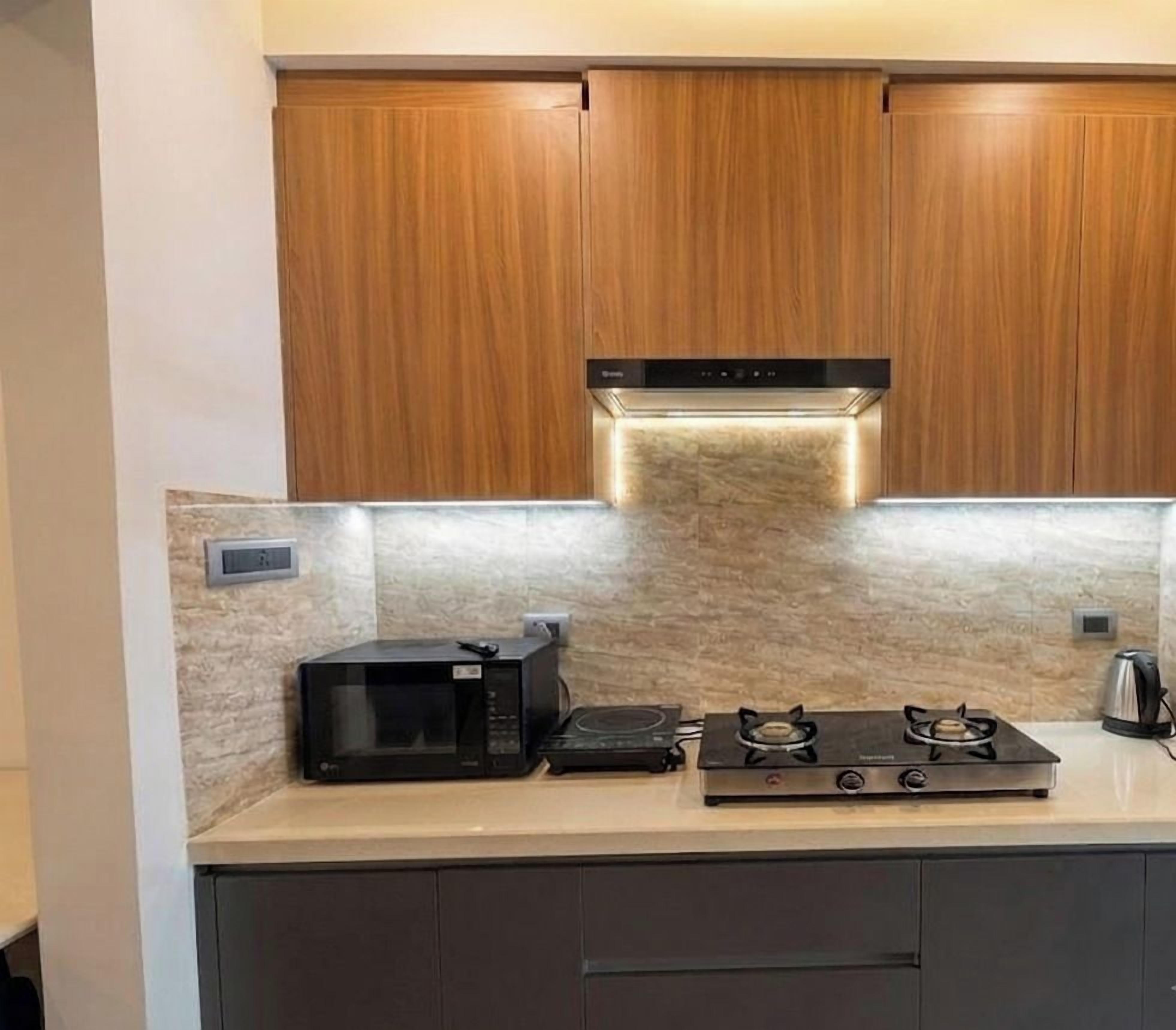 Une cuisine avec des meubles en bois, un four à micro-ondes, une cuisinière à gaz et un four encastré.