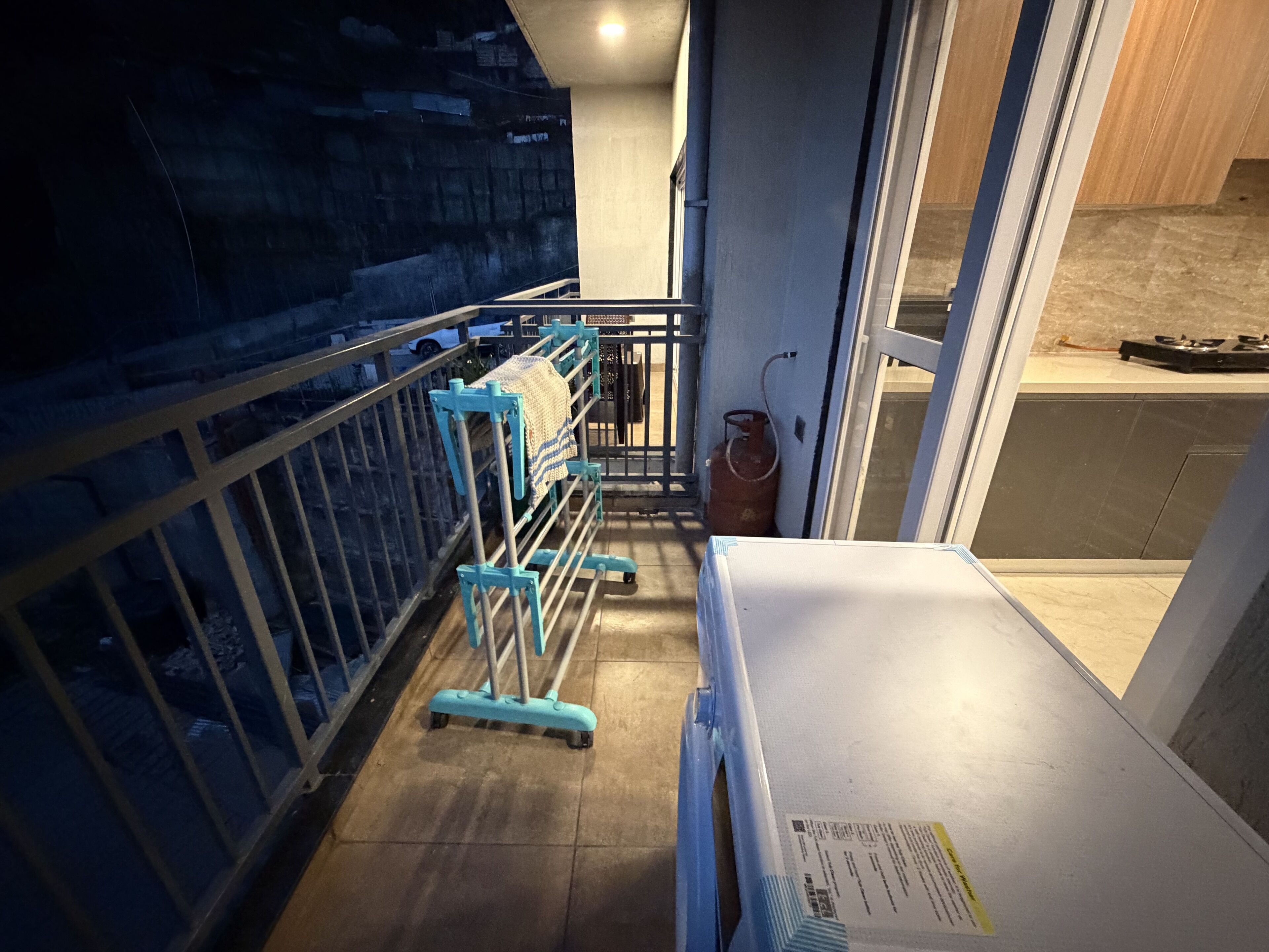 A narrow corridor with a metal railing, a white bench, and a gas cylinder.
