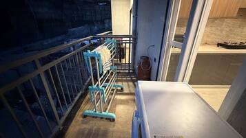 A narrow corridor with a metal railing, a white bench, and a gas cylinder.