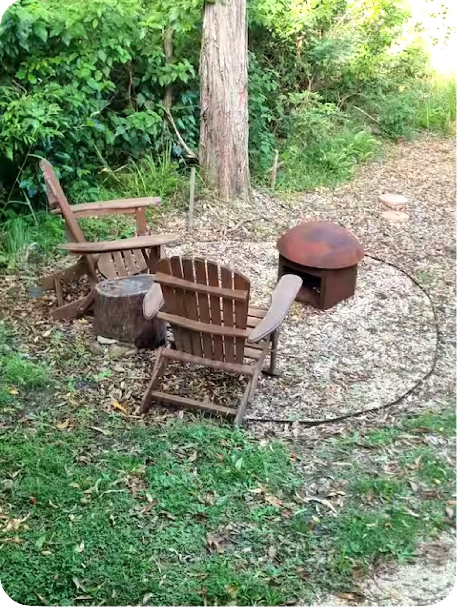 A rustic outdoor seating area with a wooden chair and a metal table, surrounded by natural foliage.