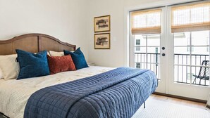 Ein Schlafzimmer mit Bett, Kissen, Deckenventilator und einer Schiebetür zum Außenbereich.