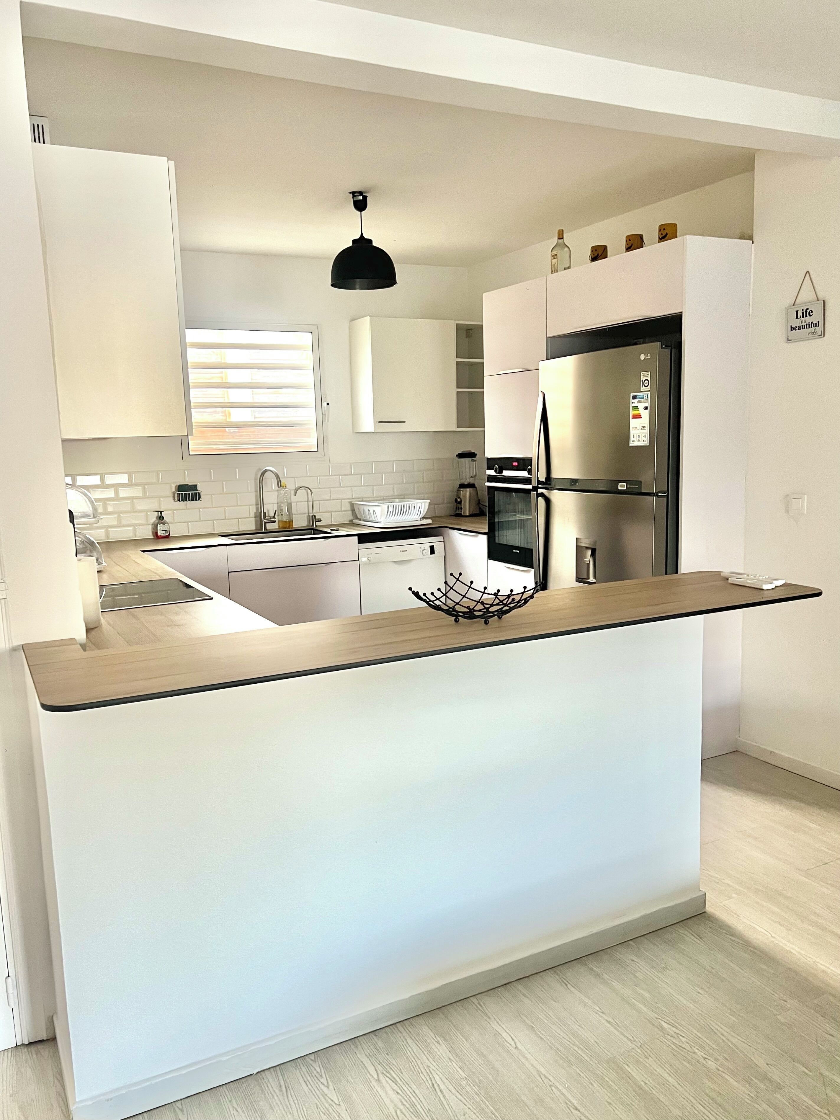 A modern kitchen with white cabinetry, a central island, and a built-in oven.