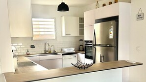 Una cocina moderna con armarios blancos, una isla central y un horno empotrado.