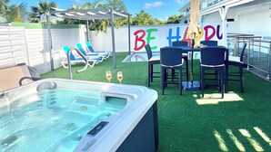 Un patio trasero con un jacuzzi, sillas de descanso y una piscina.