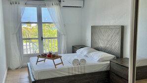 Un dormitorio con cama, mesita de noche, cortinas y un equipo de aire acondicionado.