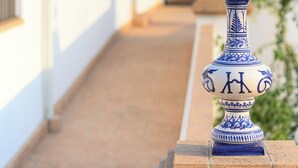 A narrow pathway flanked by white buildings with a blue decorative urn in the foreground. - Room 3A (Doña Mencía)