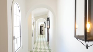 A hallway with a checkered floor, white walls, and a door on the left. - Room 3A (Doña Mencía)