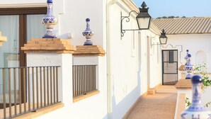 A narrow pathway leading to a building with white walls and blue decorative vases on the facade. - Room 3A (Doña Mencía)