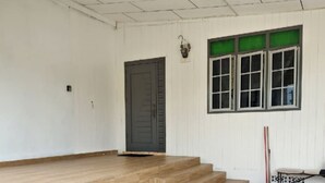 Een gebouw met een houten trap die naar een deur leidt, een versierd vloer en een raam met groen getinte glas.