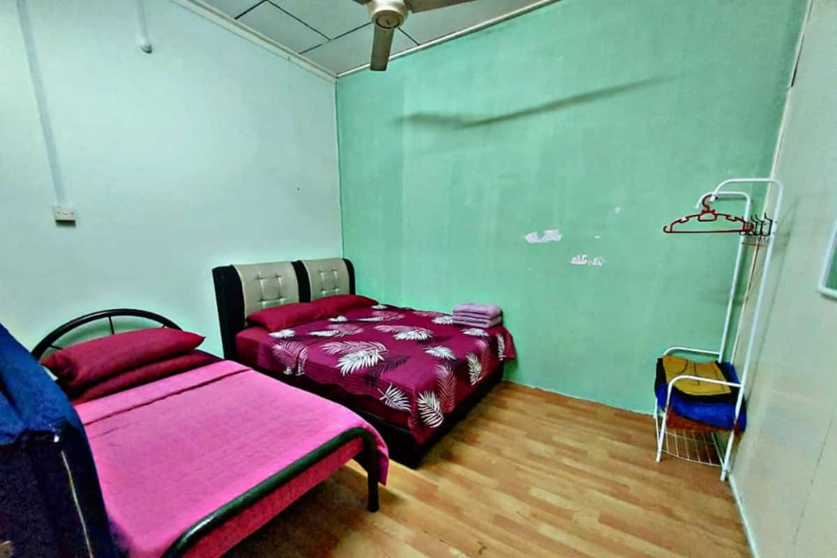 A room with two beds, a ceiling fan, a small table, and a wall-mounted drying rack.