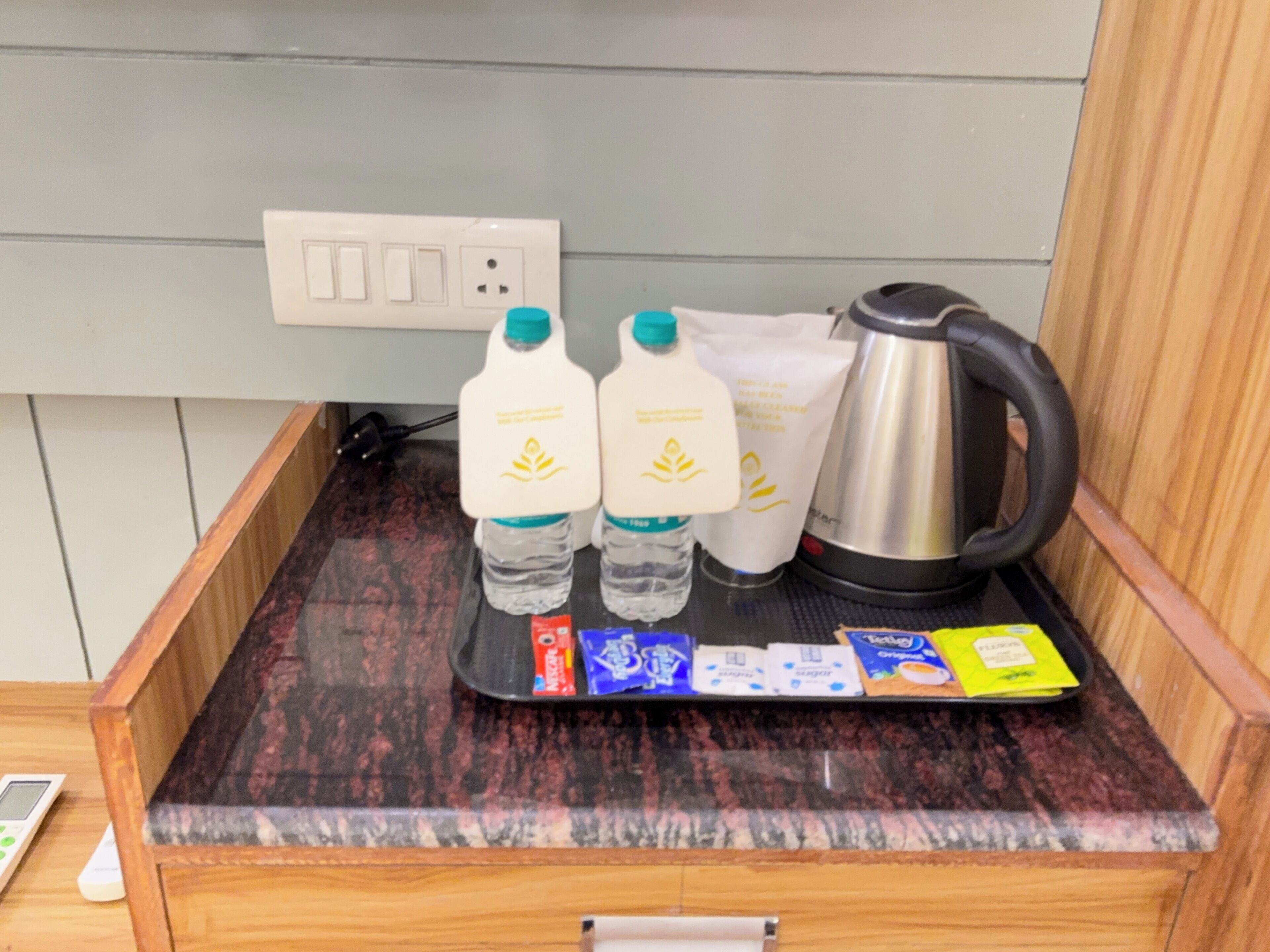 A kitchen counter with a coffee maker, two water bottles, and a tray with food packets.