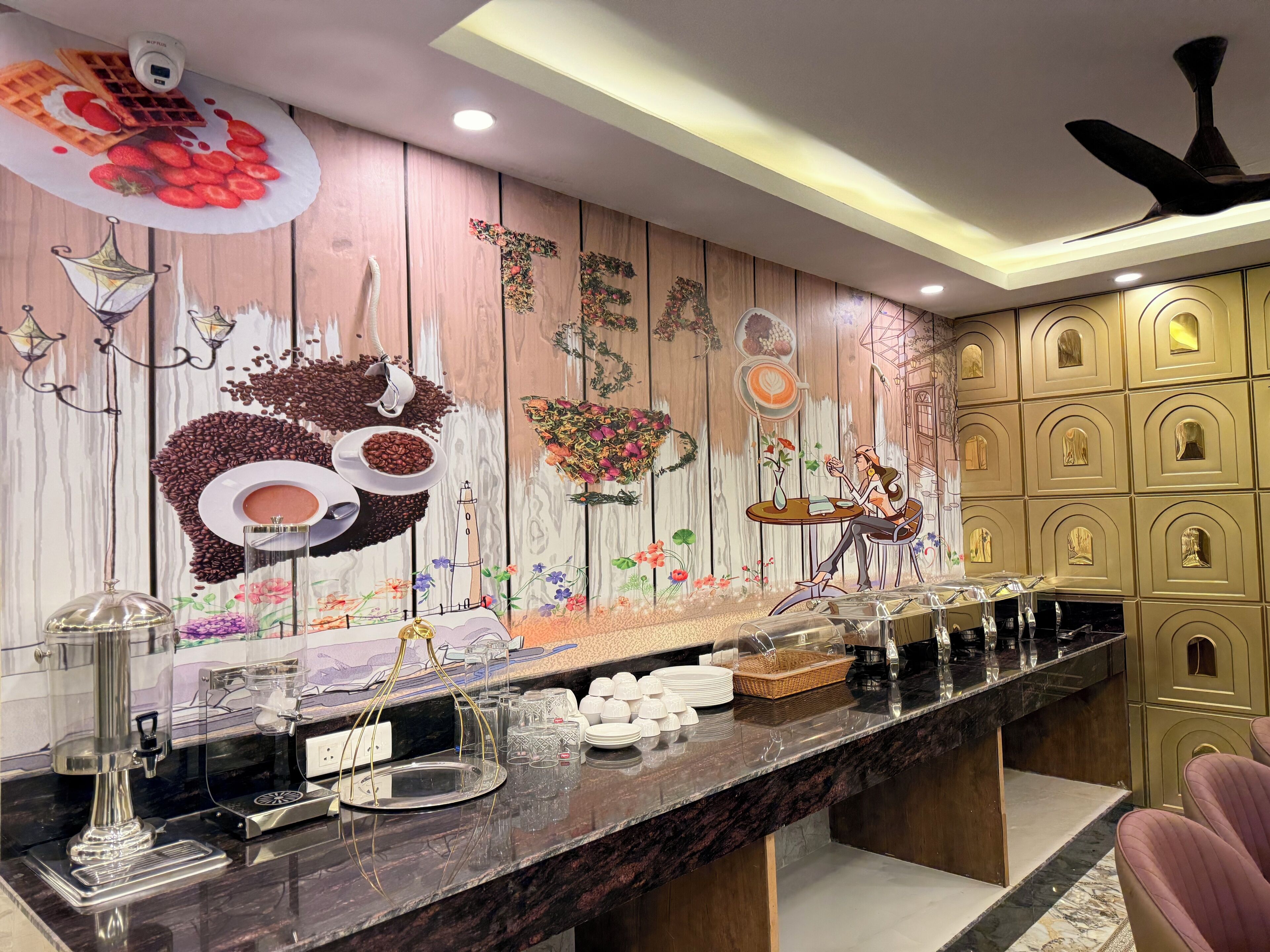 Uma área de buffet com um mural de madeira, uma máquina de café e diversas opções de comida.