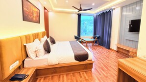 A hotel room with a bed, bedside table, chair, desk, TV, and a window with curtains. - The Prominence Hotel Greater Noida (Greater Noida)